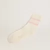 Calcetines blancos con acabado desgastado, logotipo rosa claro y rayas.