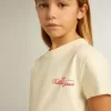 Camiseta de algodón para niña en blanco desgastado con bordado rojo en el pecho