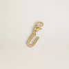 Charm con la letra U en latón dorado con cristales