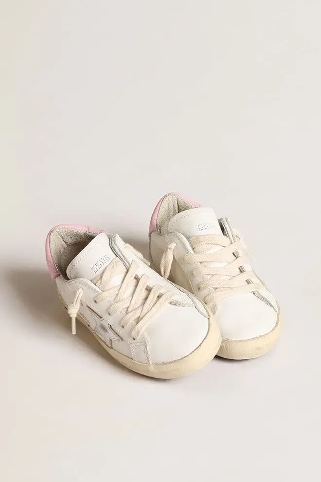 Junior Super-Star en piel blanca con estrella metálica plateada y lengüeta rosa en el talón Junior Super-Star en piel blanca con estrella metálica plateada y lengüeta rosa en el talón